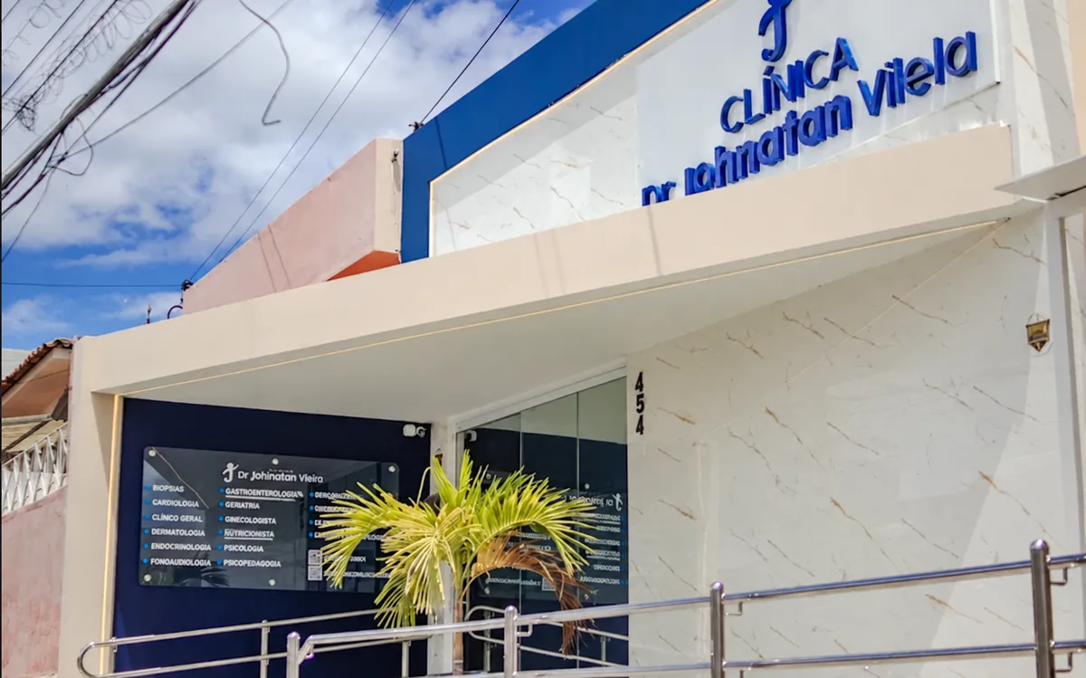 Fachada da Clínica Dr. Johnatan Vilela na R. Cap. Dé, 454, em Caruaru, com letreiro azul, placa das especialidades e rampa de acesso