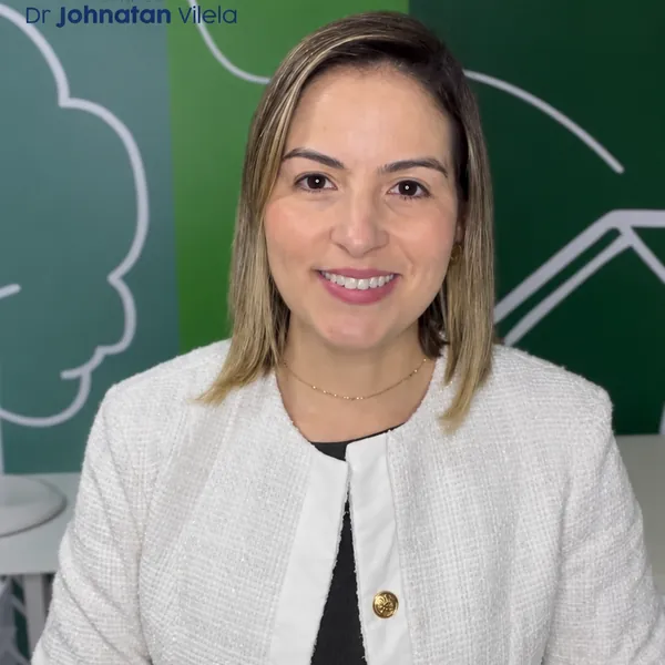 Profissional sorrindo em frente à parede ilustrada da Clínica Dr. Johnatan Vilela