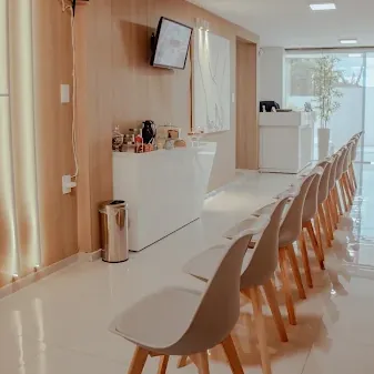 Recepção da Clínica Dr. Johnatan Vilela com cadeiras brancas e bancada de café