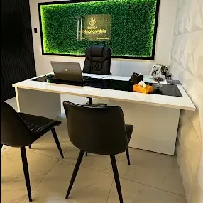 Consultório com mesa branca e painel verde iluminado com a logomarca da clínica