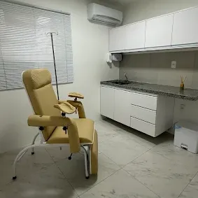Sala de procedimentos com poltrona reclinável, pia e armários brancos
